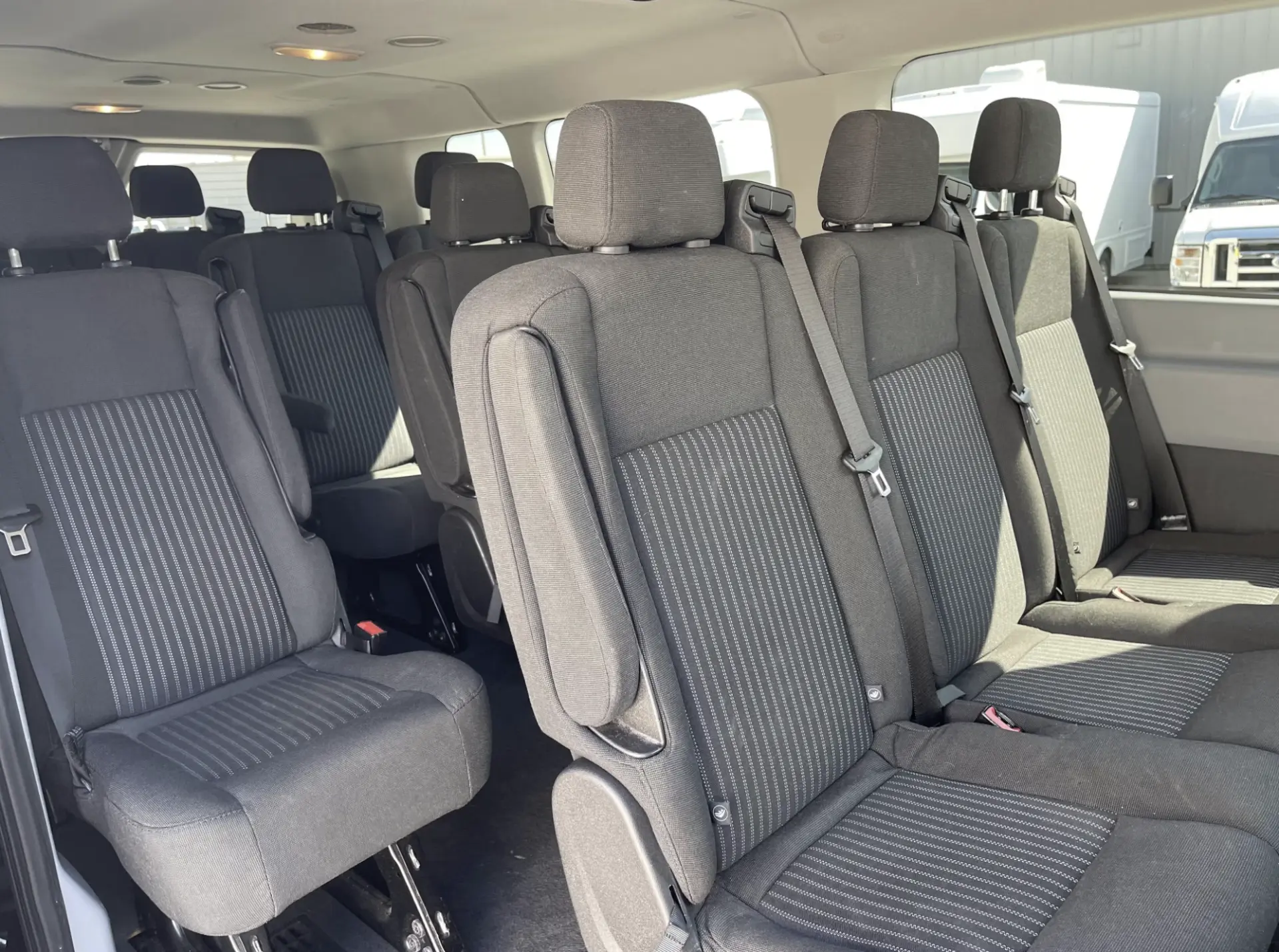 Rows of cloth passenger seats inside the Ford Transit 350 van